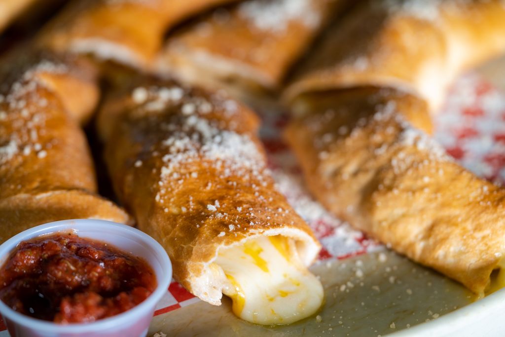 Pizza bones with melted cheese and a cup of red dipping sauce